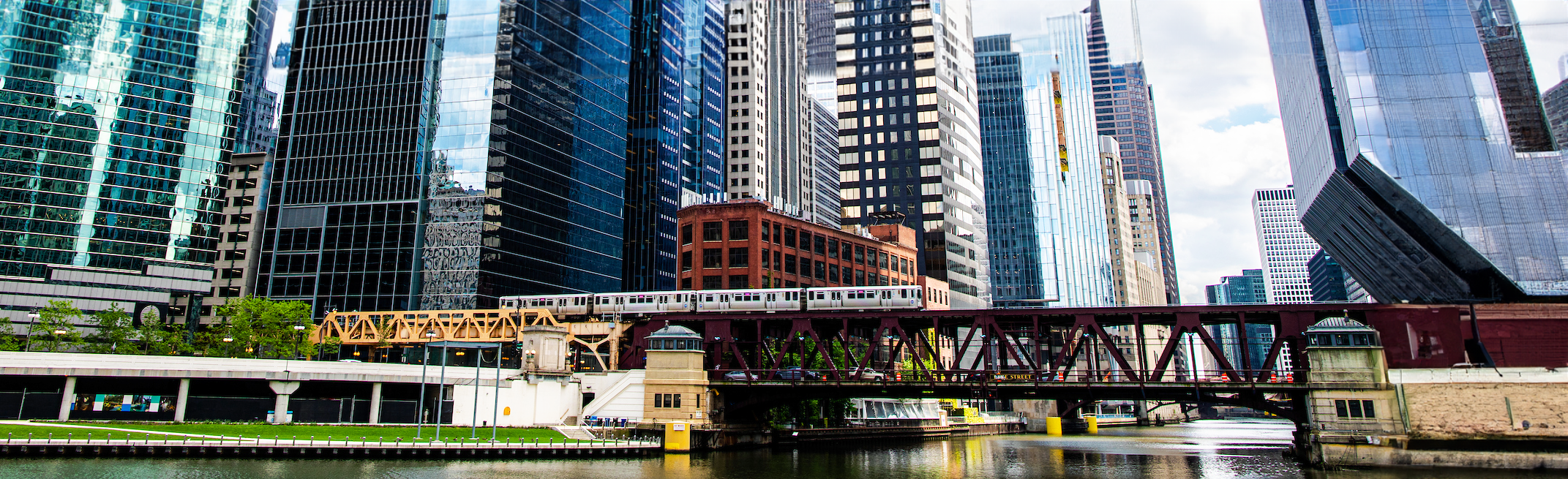 A scene of downtown Chicago, including the river, the riverwalk, the CTA train
